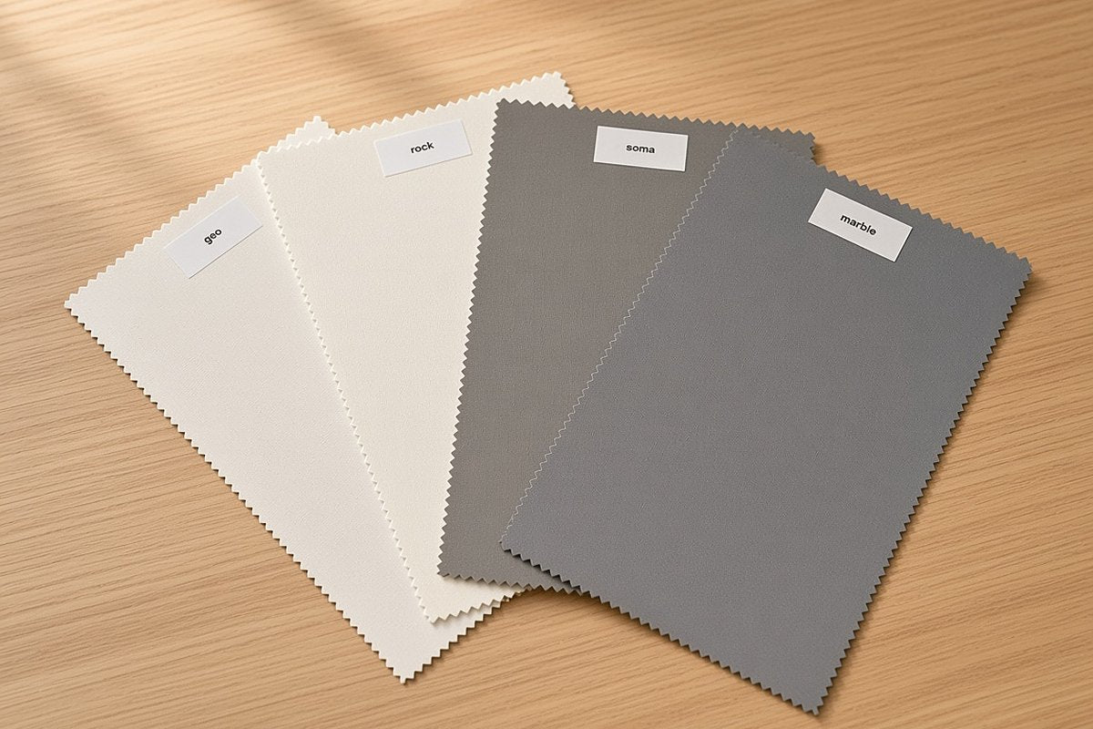 Four roller blind fabric swatches fanned on a timber table